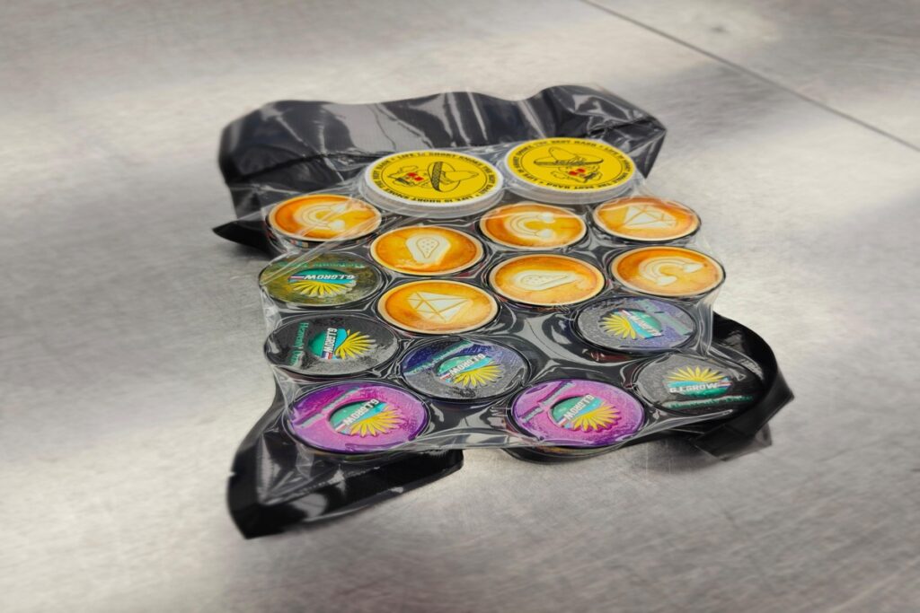 Vacuum sealed pack of live rosin jars with branded lids on stainless steel surface